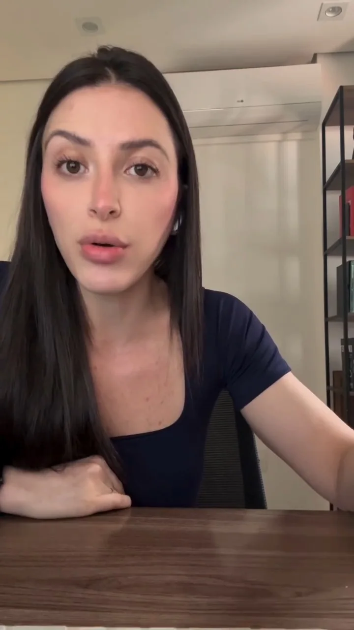 Deborah Moss de blusa azul-marinho, olhando para a câmera à mesa de madeira, com luz natural de janela